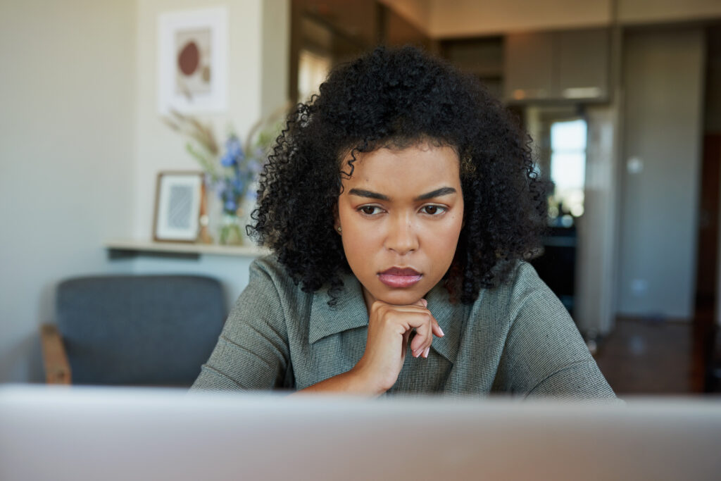 Young woman looking worried while researching pregnancy options on laptop at Sienna Women’s Center.